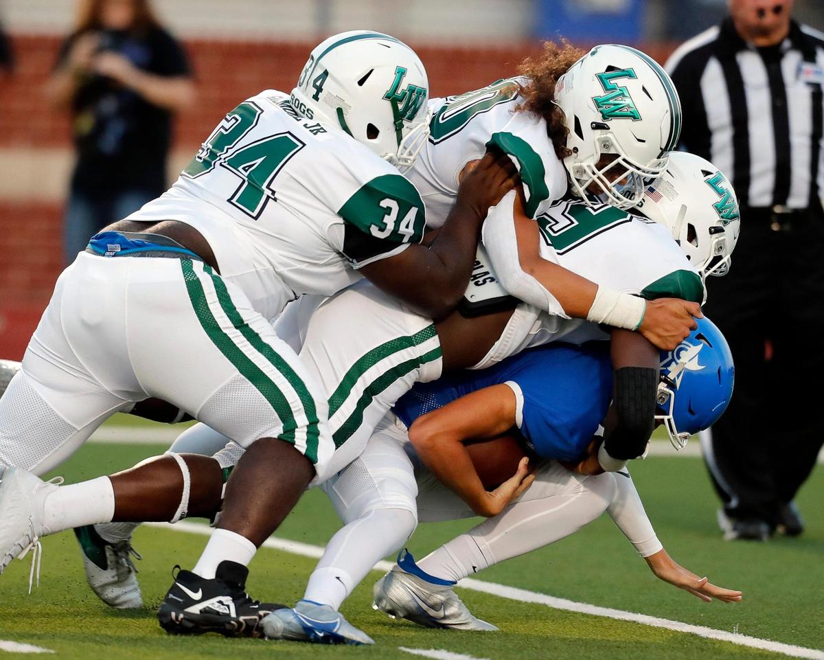 Joshua quarterback Jaydin Pool (5) is swallowed in the backfield by the Lake Worth defense including lineman Terrance Gilmore (34) and defensive end Exauce Mbakula (19) for a ten yard loss during a high school football game at Owl Stadium in Joshua, Texas, Friday, Sept. 10, 2021. Lake Worth led Joshua by one at the half. (Special to the Star-Telegram Bob Booth)