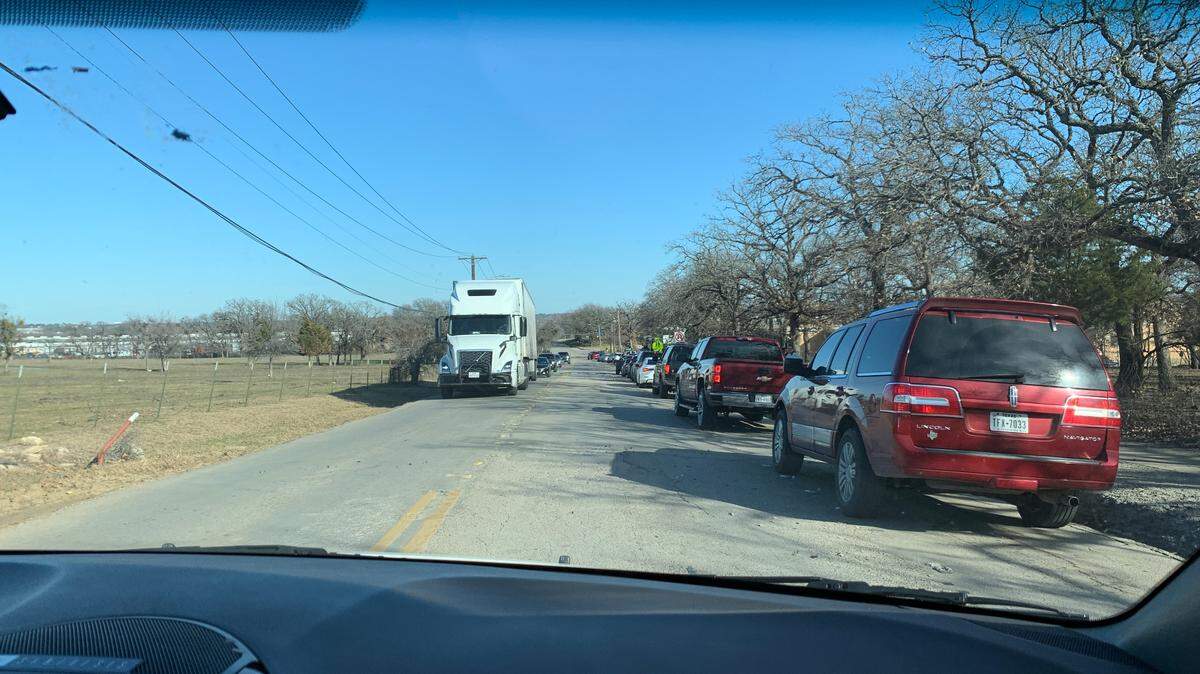 A freight truck driving past W.M. Green Elementary School on Feb. 1, 2024. A Fort Worth Police Department patrol car sits further up the road.