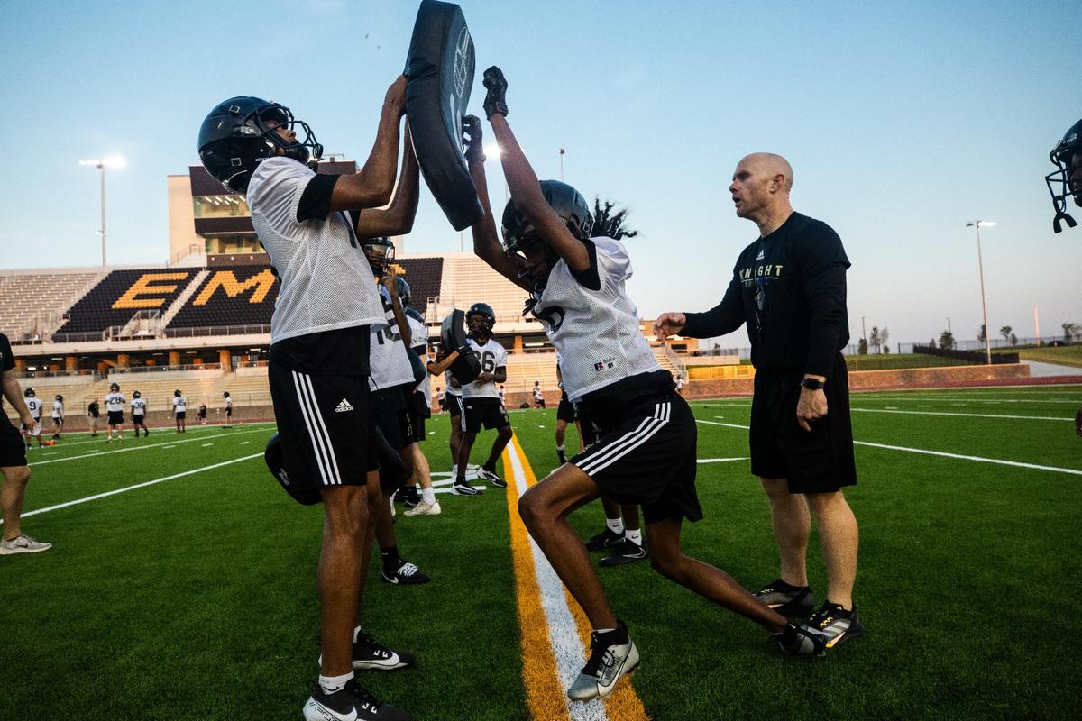 Eagle Mountain High School head coach Jeremy Mullins leads players through defense drills on Monday, August 5.