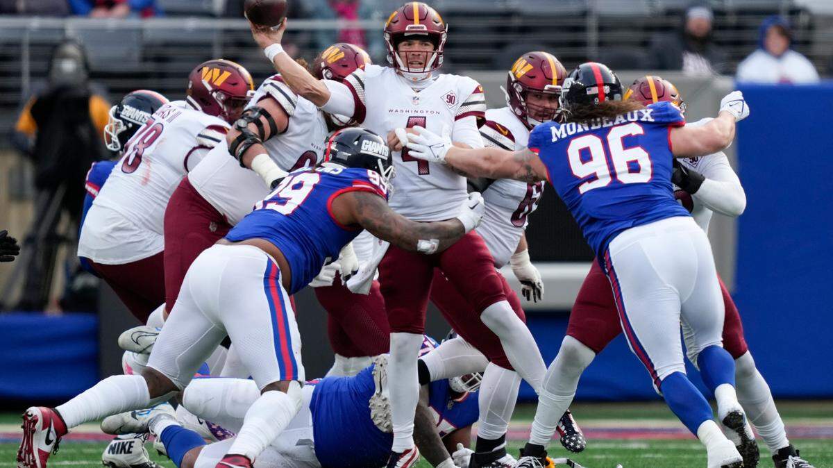 Washington Commanders quarterback Taylor Heinicke (4), center, throws under pressure from New York Giants’ defenders during Sunday’s game in East Rutherford, N.J.