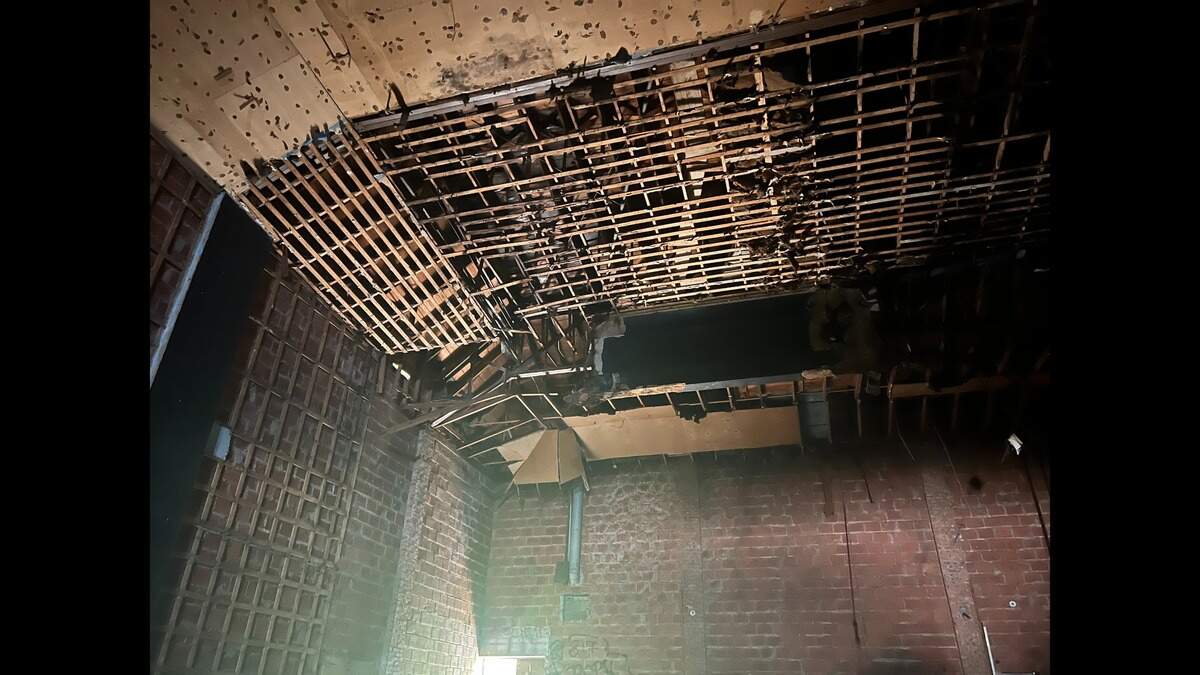 The ceiling of an old movie theater with exposed rotting studs and brick. 