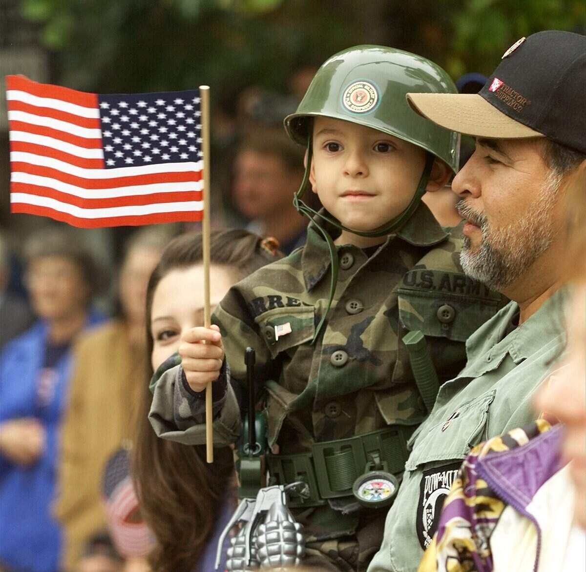 Nov. 10, 2001: Daniel Torres, 5, waves a flag as he watches the parade from the arms of his father, Ben Torres, at the Veteran’s Day parade in downtown. Ben is a Vietman veteran who served in the Army.