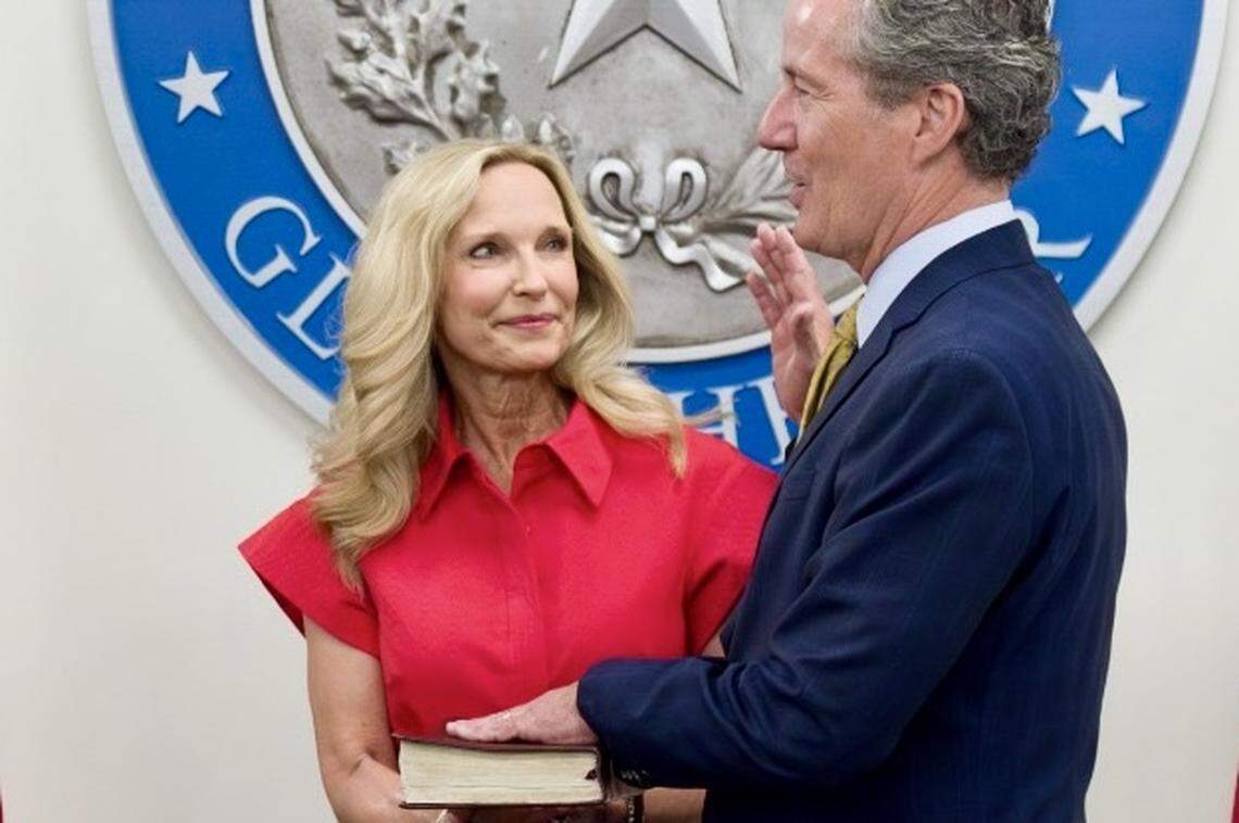 Former State Sen. Kelly Hancock of Westlake is sworn in as acting Texas comptroller by Comptroller Glenn Hegar (out of scene to left) as his wife, Robin, looks on, June 19, 2025.