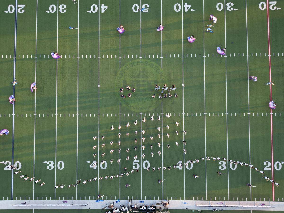 An aerial view straight down of a football field with configurations of the band members seen.