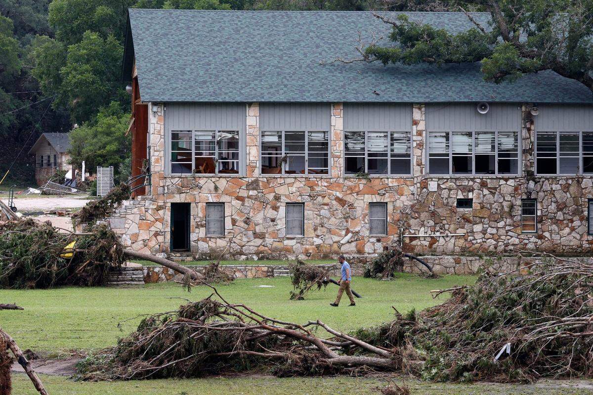 A man walks by a building at Camp Mystic on Saturday, July 5, in Hunt, Texas. A flash flood swept through the area early Friday morning. More than 100 people died in flooding across the state, mostly near the Guadalupe River. Camp Mystic, a Christian summer camp for girls in Central Texas, confirmed at least 27 campers and counselors are believed to have died.