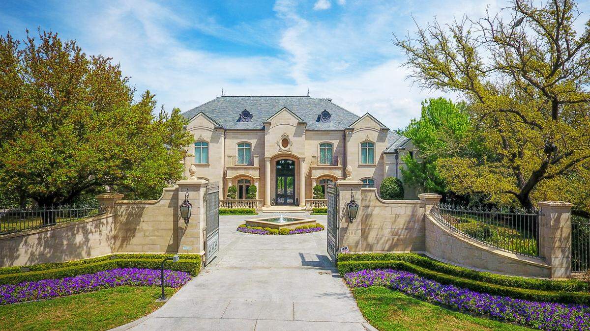 A limestone-adorned mansion in Fort Worth, guarded by a wrought iron gate. 