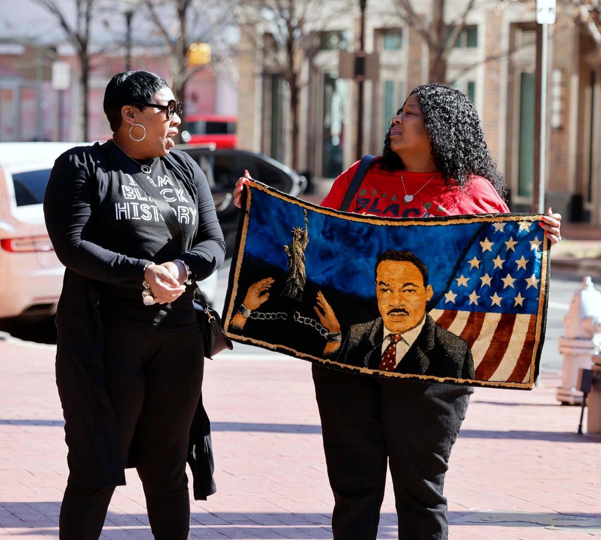 Sisters, Shanette Smith and Latricia Stewart display a tapestry of Martin Luther King Jr. that has been in their family for over 60 years during the 2024 MLK parade in downtown Fort Worth.