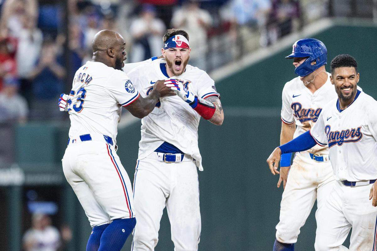 Texas Rangers catcher Jonah Heim (28) celebrates with his teammate Adolis Garcia (53) after hitting a walk off single at the bottom of the tenth inning to win their season opener against the Chicago Cubs 4-3 at Globe Life Field in Arlington on Thursday, March 28, 2024.