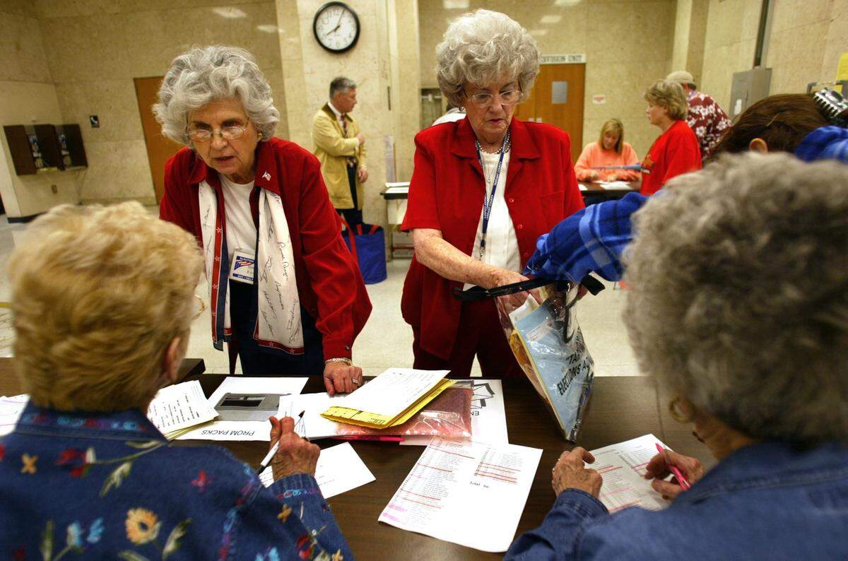 Voting official, Marilyn Basham, facing left, turns in her precincts votes as election deputy Jeanne Lyon, facing right, checks her official voting bag on election night November 2, 2004 at the Tarrant County Courthouse. Two other election deputies, Mary Hawpe and Mattie Johnson, also help double check the voters bags.