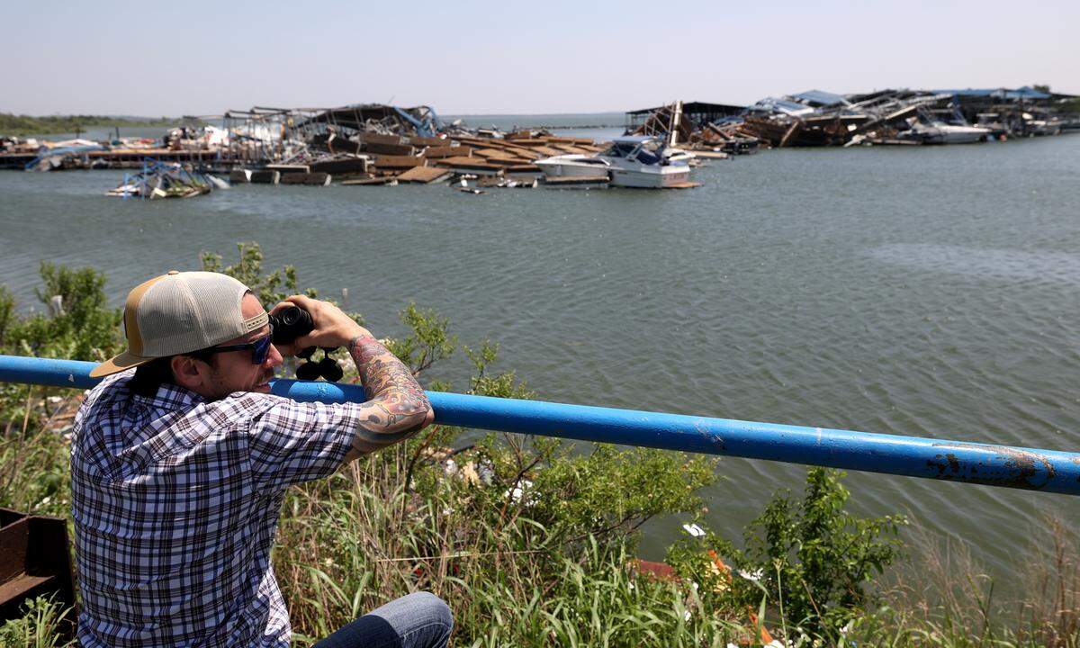 Bill Little uses binoculars to try to locate his boat amid the debris on Sunday, May 26, 2024. Severe storms damaged multiple boat slips at Ray Roberts Marina.