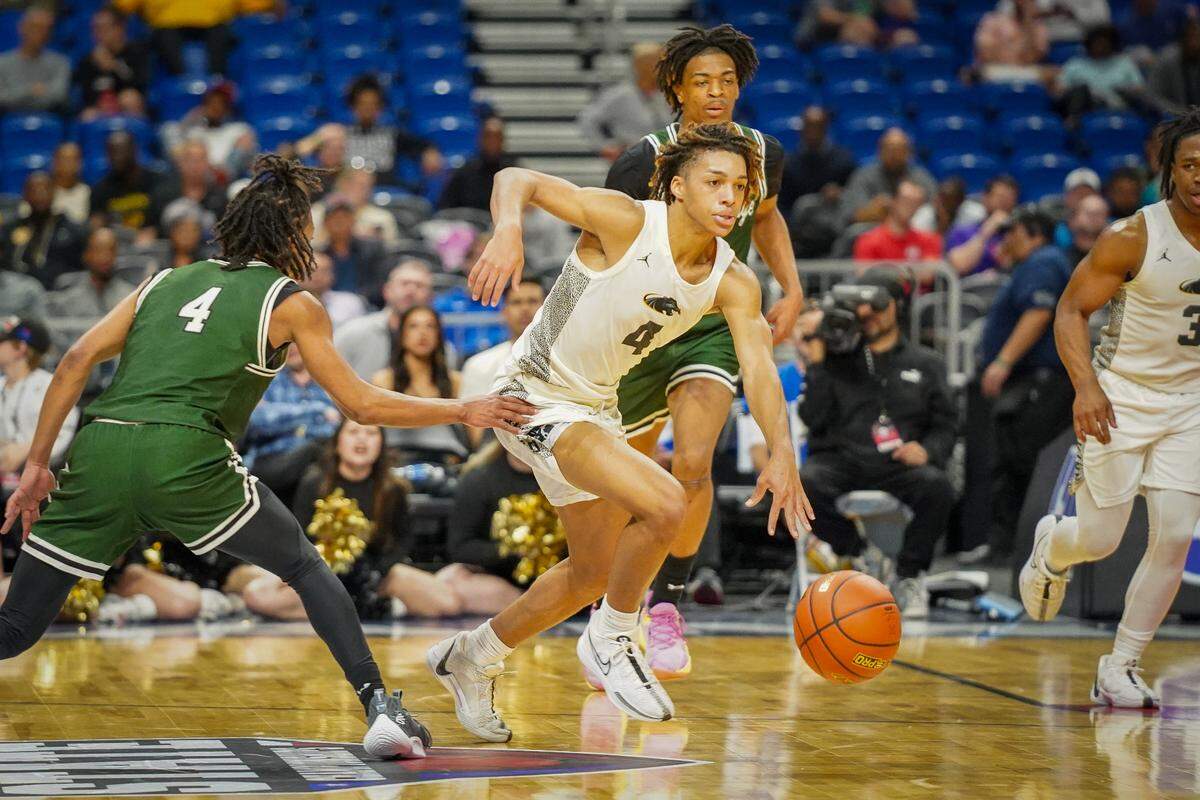 Plano East guard Jordan Mizell (4 in white) dribbles up court past Mansfield Lake Ridge’s Amir McMillan (4 in green) in a Class 6A state semifinal on Friday, March 8, 2024 at the Alamodome in San Antonio, Texas. Plano East downed Lake Ridge 61-45.