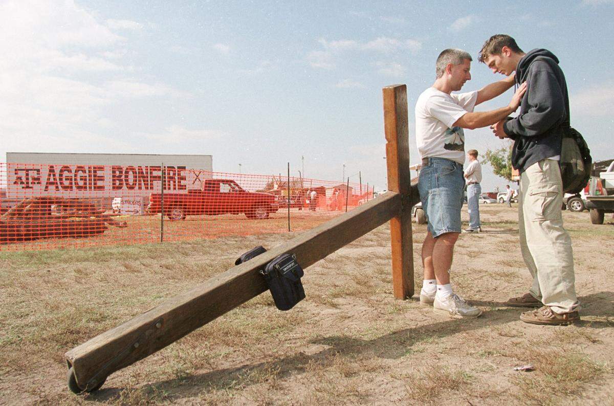 Bob Hanus Jr. of Utopia prays with Jonathan Gibson, a 19-year-old student, for the familes of the victims who were killed in the collapsed bonfire at Texas A&M. Hanus carries this cross with him ‘to remind people of hope.’