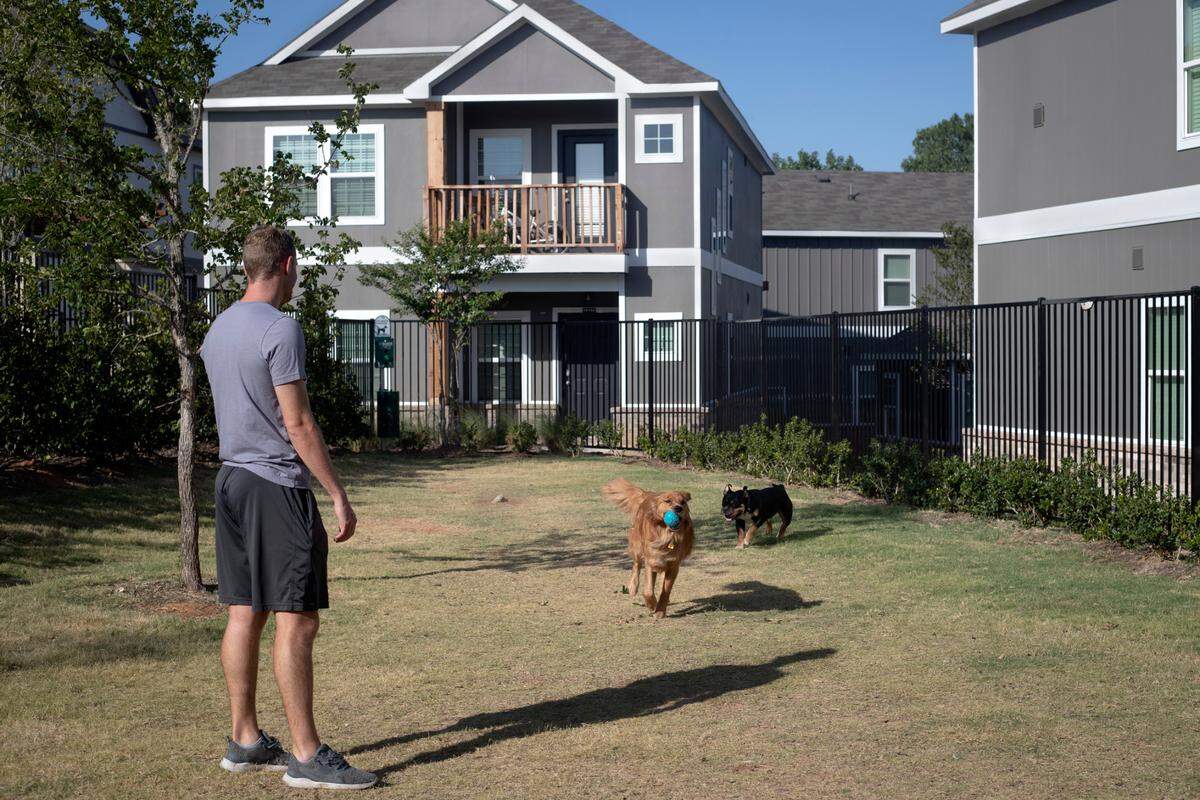 Ty Sawka plays fetch with neighborhood dogs at the Cottages at Bell Station in Hurst, Texas, on July 5, 2022.