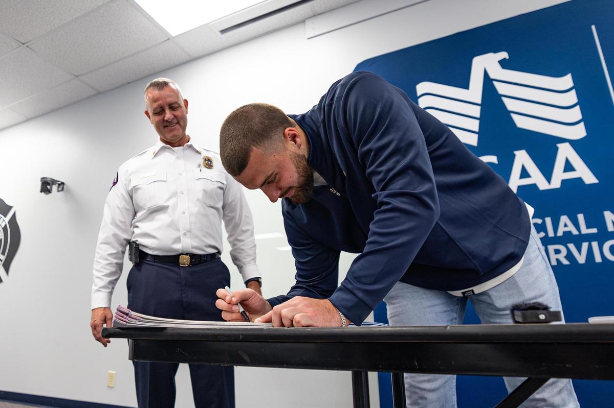 Dallas Cowboys tight end Jake Ferguson signs an autograph for Arlington Fire Chief Bret Stidham following a Turkey Fryer Fire Safety demonstration at the Arlington Fire Department Training Facility Station 14 in Arlington on Tuesday, Nov. 14, 2024.