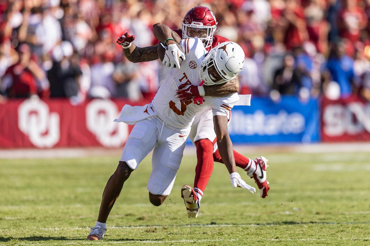 Texas wide receiver Ryan Wingo (5) is tackled from behind fro Oklahoma defensive back Woodi Washington (5) after a long gain in the first half of an NCAA football game at the Cotton Bowl in Dallas on Saturday, Oct. 12, 2024.