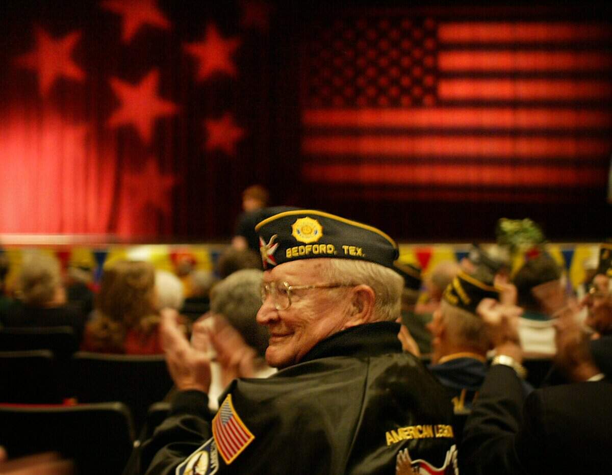 Nov. 10, 2005: R.C. Sloan of Euless, who served in the U.S. Navy from 1950 to 1955, joins others to applaud for people being honored at the Veterans Day ceremony at Grapevine High School.
