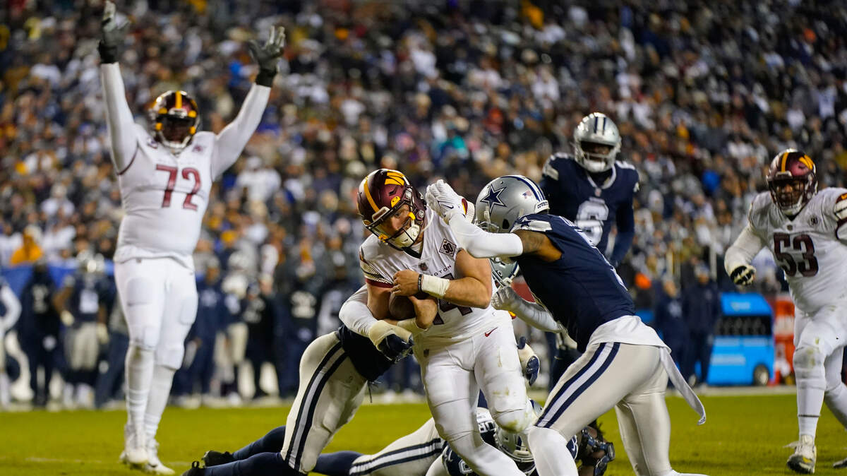 Washington Commanders quarterback Sam Howell (14) scores a touchdown against Dallas Cowboys cornerback Trevon Diggs (7) during Sunday’s game in Landover, Md.