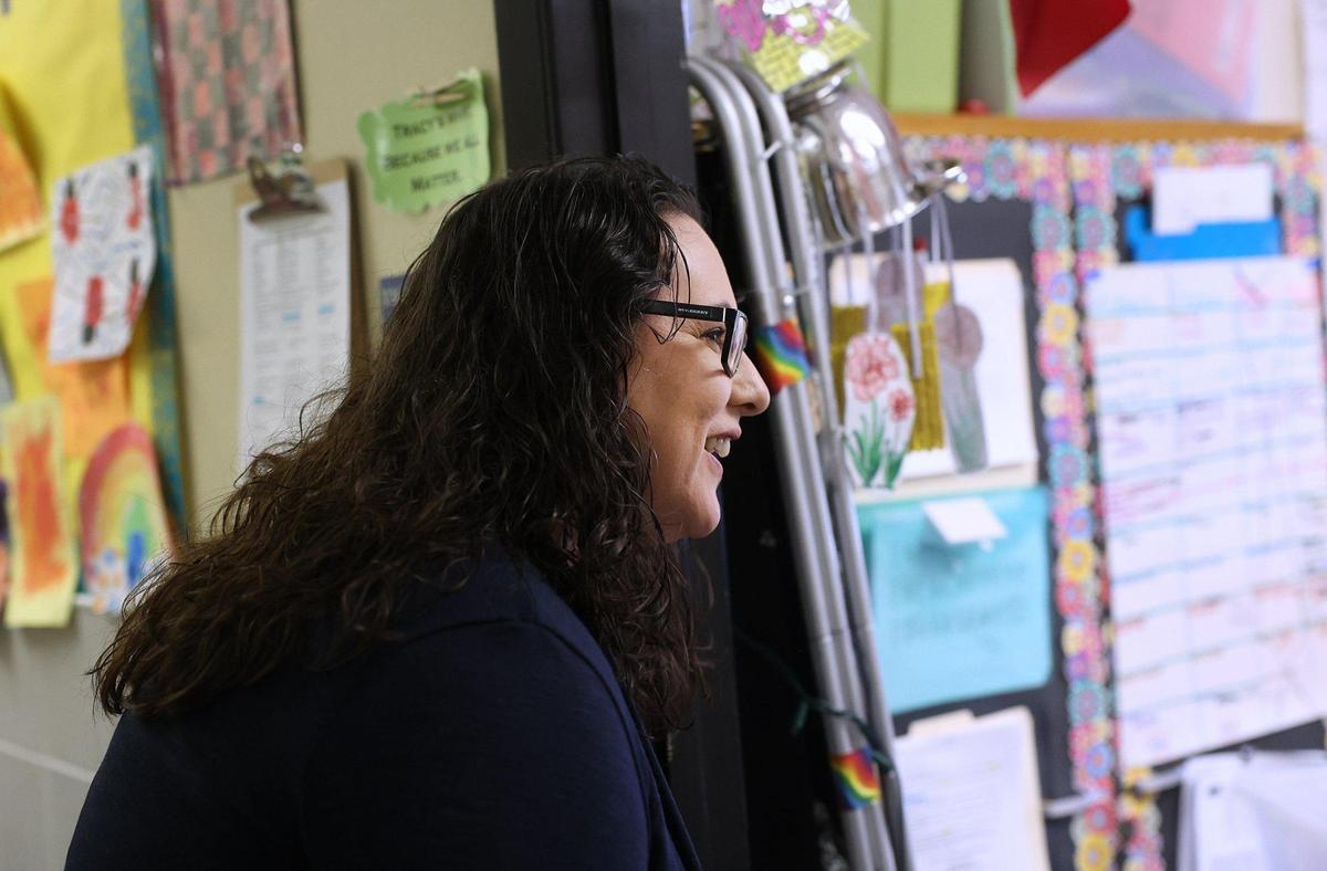 A tight shot of Ramsey as she peaks into a classroom from a hallway with artwork on it.