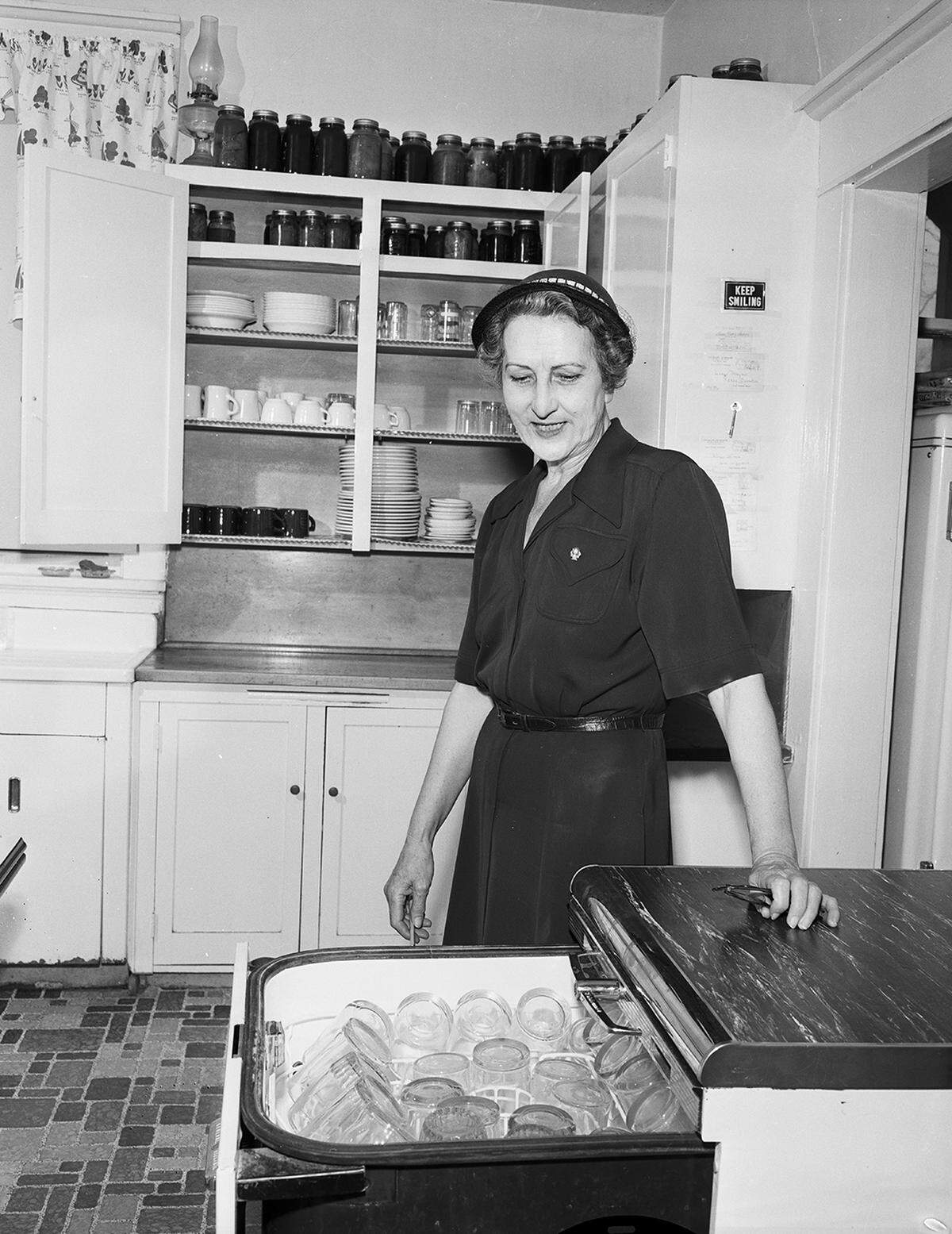 March 23, 1954: Mrs. Rhoda Bodycoat, city sanitarian, inspects an automatic dishwasher in a care home kitchen, a recommended item.