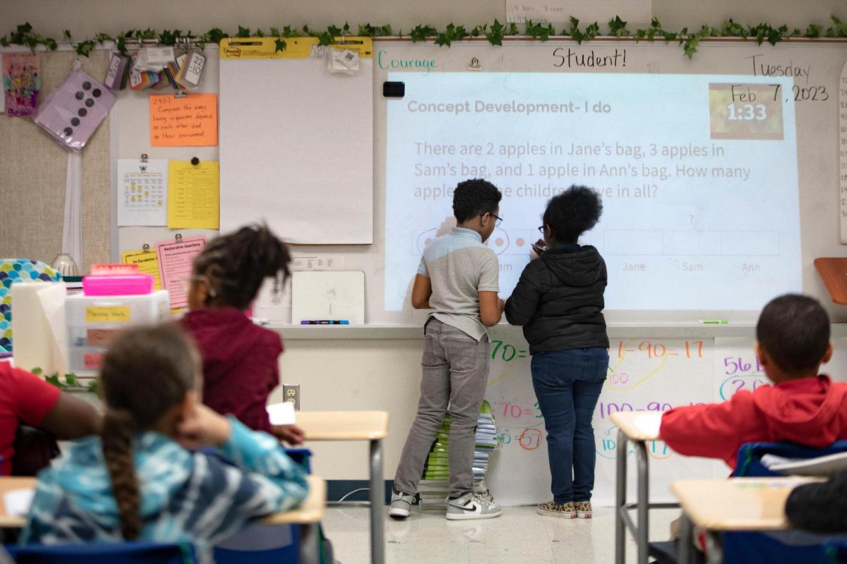 Students Kayden Fletcher and Shukri Mohamed Abdullahi solve a math problem on a whiteboard at David L. Walker Elementary on Feb. 7.