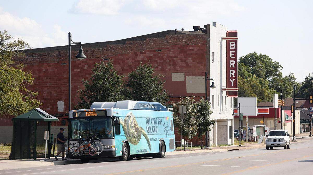 An old movie theater with a city bus in front of it.