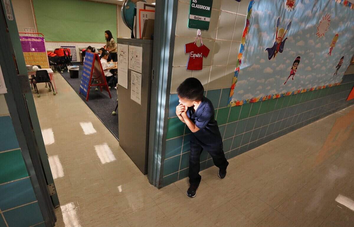 Aug. 24, 2015: With first-day jitters, a timid Isaac Lugo, reluctant to go in to class, peeks around the doorway of his kindergarten classroom as school children returned to school at Diamond Hill Elementary in Fort Worth.