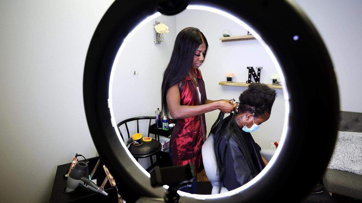 When salons closed during the COVID-19 pandemic, Nai Packnett, shown braiding Eve Mbodji’s hair, turned to wig-making, something she could do at home and sell online.