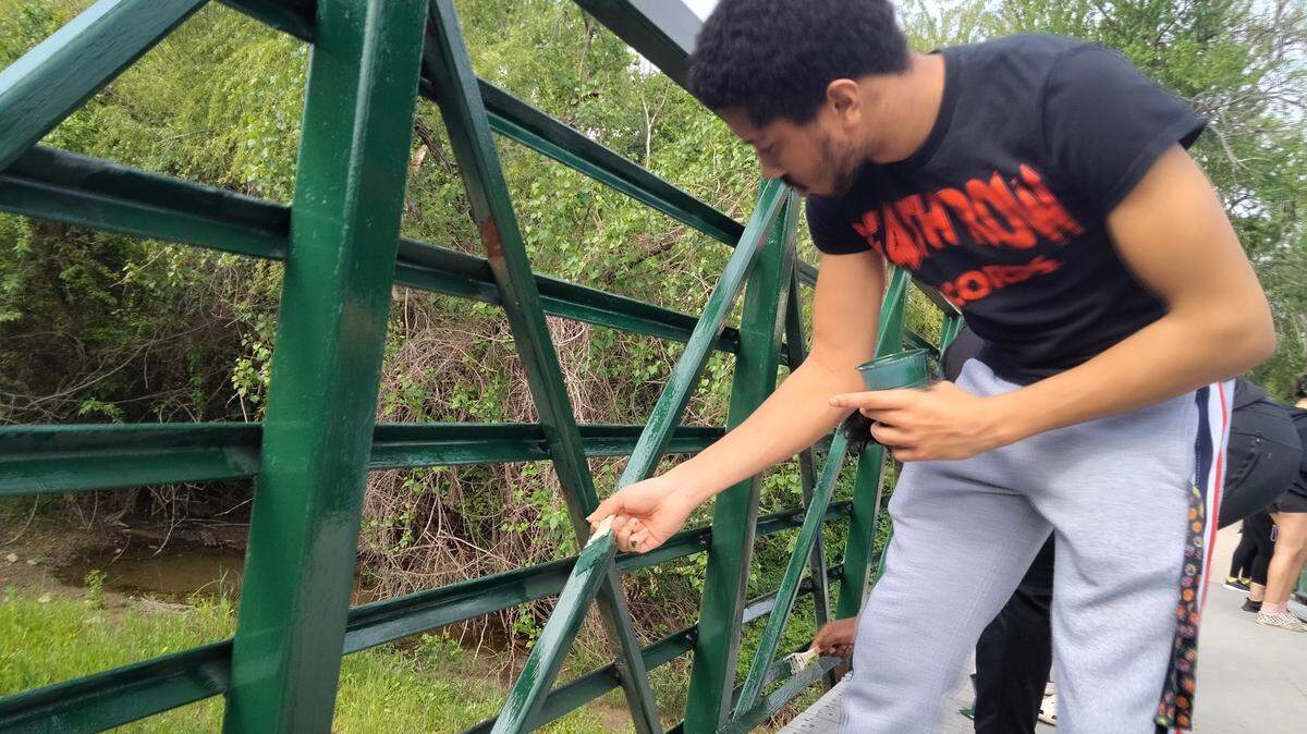 Davion Arion, a Saginaw Chisholm Trail High School Senior, paints a bridge on a trail at Marine Creek Lake as part of the first “Off The Trail” project in which students at the high school and its two feeder middle schools worked to clean up the area.