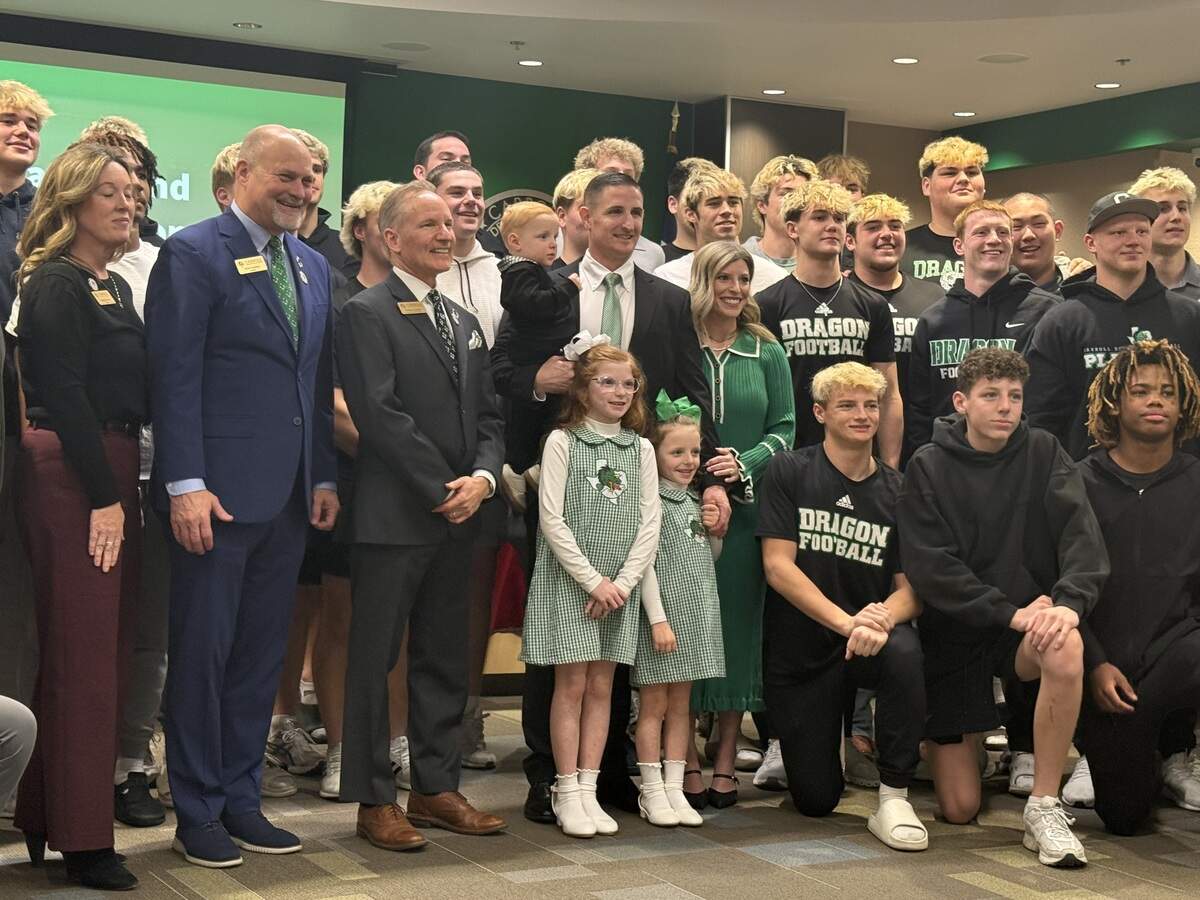 Newly promoted Southlake Carroll head coach Lee Munn poses for a photo with the Carroll ISD Board of Trustees, his family and Dragon football players at the Carroll ISD Administration Center in Southlake on Monday, Feb. 2, 2026.