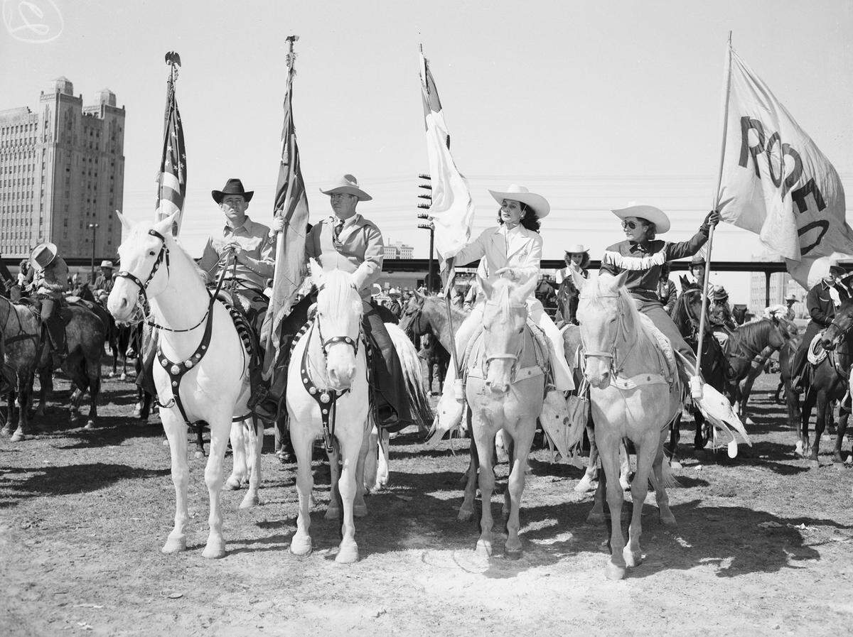 March 8, 1946: Southwestern Exposition and Fat Stock Show Parade: “Leading the longest and most colorful stock show and rodeo parade in the 50 years of the event were these four flag-bearer riders, from left: Duffy Crabtree, Great Falls, Montana. Vic Truitt, Stonewall, Oklahoma. Fay Kirkwood and Tad Lucas, both of Fort Worth.  In the distance is the Fort Worth Texas & Pacific Railway station depot. 