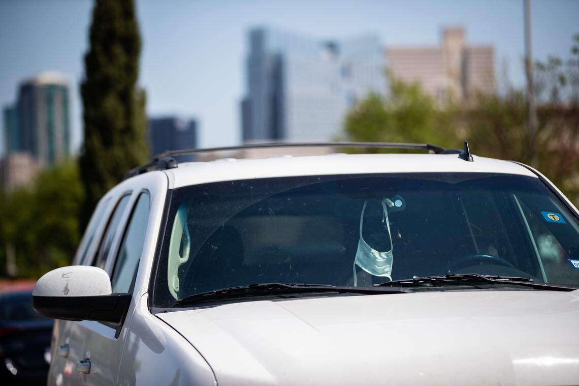 A mask hangs from a rearview mirror of a car amid the coronavirus outbreak Friday, April 10, 2020, in Fort Worth.