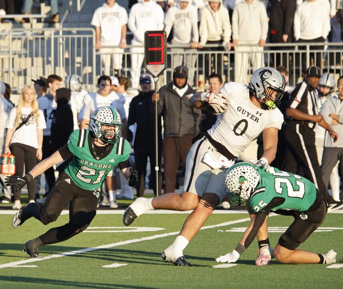Southlake Carroll linebacker Robbie Ladd (21) and defensive back Gavin Strange (25) team up against Denton Guyer tight end / defensive end Zane Rowe (0) for the tackle during the second half of a UIL Class 6A Division II Quarterfinal on Saturday Dec. 06, 2025 at Crowley ISD Multi-Purpose Stadium in Fort Worth, Texas.