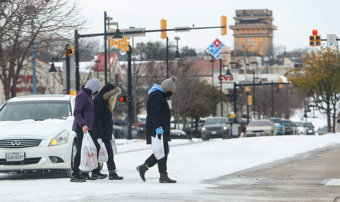 A group of pedestrians cross West Berry Street after stocking up at Walgreens on Feb. 16, 2021, in Fort Worth.