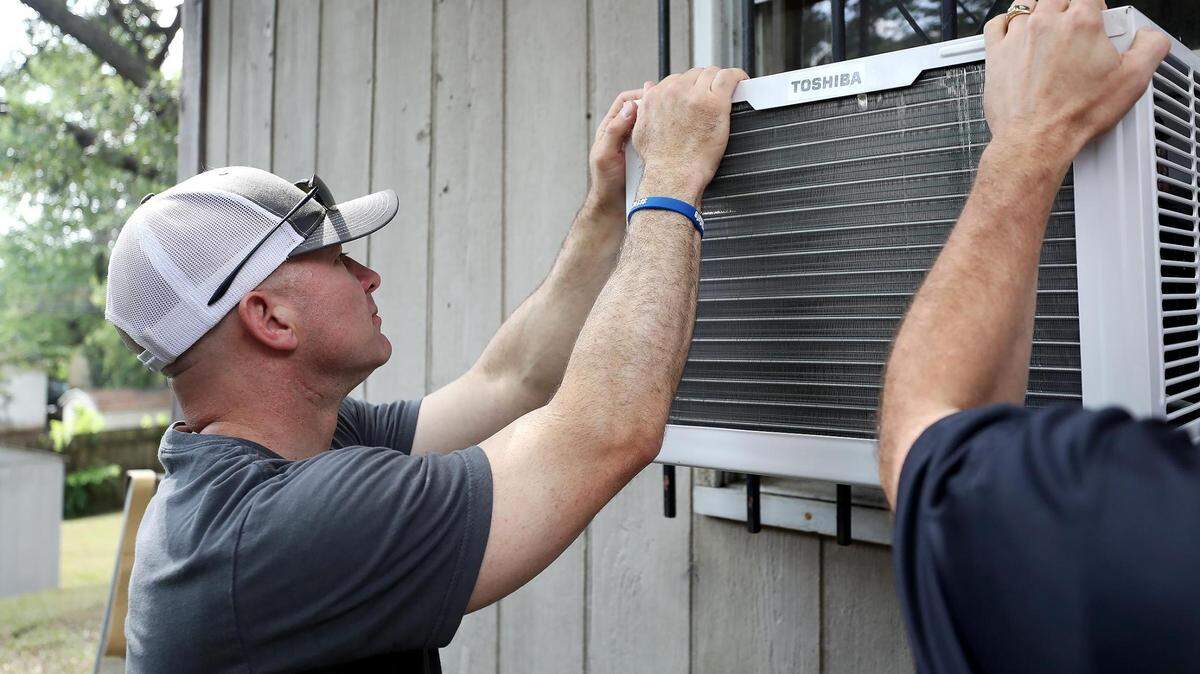 Fort Worth Police Chief Neil Noakes helps to install an air conditioning unit into into Lanell Hayward HarrisÕ southeast Fort Worth home on Thursday, July 15, 2021. 