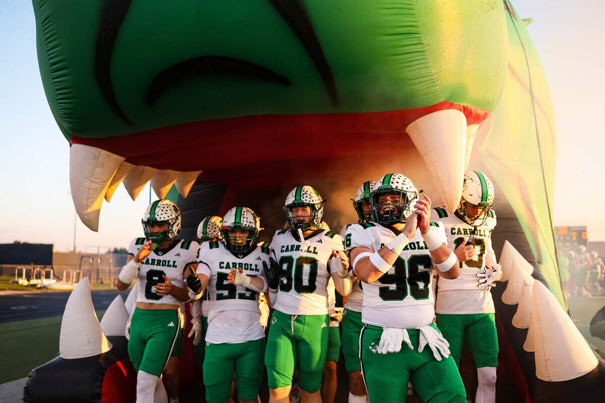 Southlake Carroll players clap and stand underneath their dragon runout tunnel before a district matchup between Southlake Carroll and Timber Creek at Keller ISD Stadium on Thursday Sept. 25, 2025.