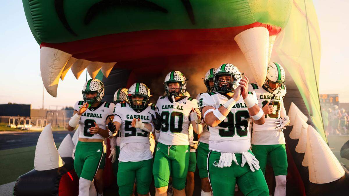 Southlake Carroll players clap and stand underneath their dragon runout tunnel before a district matchup against Keller Timber Creek at Keller ISD Stadium on Thursday Sept. 25, 2025.