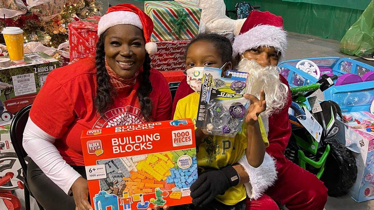 Seasons of Change founder and Executive Director Tavian Harris celebrates the Christmas season with Santa Claus and a youngster.