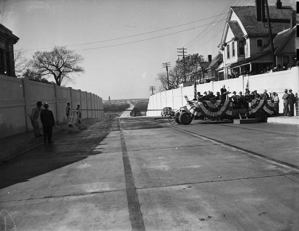 Dec. 23, 1942: A dedication ceremony to celebrate new “Gateway to West Texas,” the connection between West Lancaster Avenue and the new bridge across Clear Fork of the Trinity River, which was opened for traffic. A crowd of people are standing at the far right of the road and a few people are standing at the left. At the right, one man is standing at a podium and speaking into a microphone.