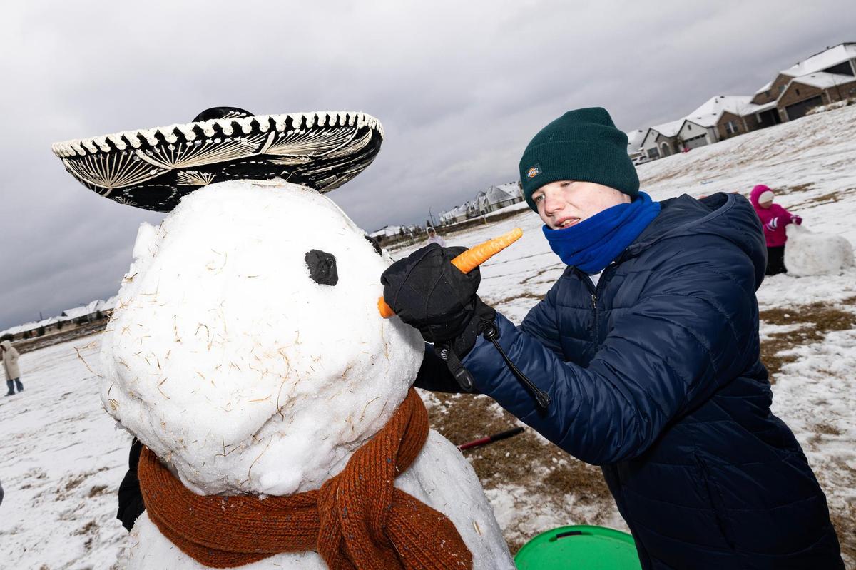 Jude Welch, 14, attaches a carrot nose to the snowman that he and his friends built at their neighborhood park in southwest Fort Worth on Friday, Jan. 10, 2025.