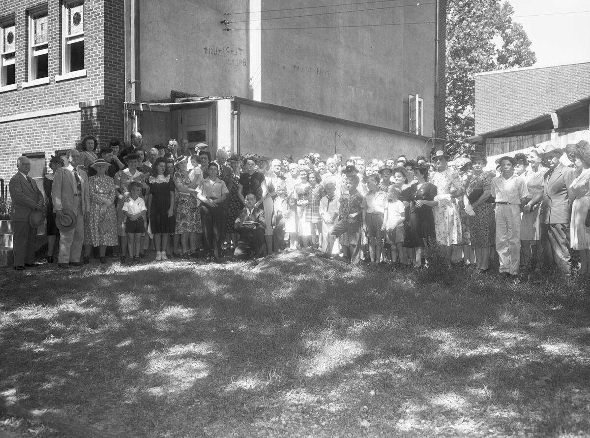 Sept. 4, 1944: A groundbreaking ceremony for an addition to the Fort Worth Boulevard Methodist Church, which will cost $12,000. A large crowd is standing in the area where the building will be constructed. Front and center in the crowd are: Norman Moore (kneeling), Mrs. W. R. Lovelace (standing behind Mr. Moore) and Dr. C. F. Hayes (right of Mrs. Lovelace). Mr. Moore, the secretary is dressed in a suit and reading from the Bible. Mrs. Lovelace, treasurer, is wearing a button-up dress. Dr. Hayes is the acting chairman of the building committee.