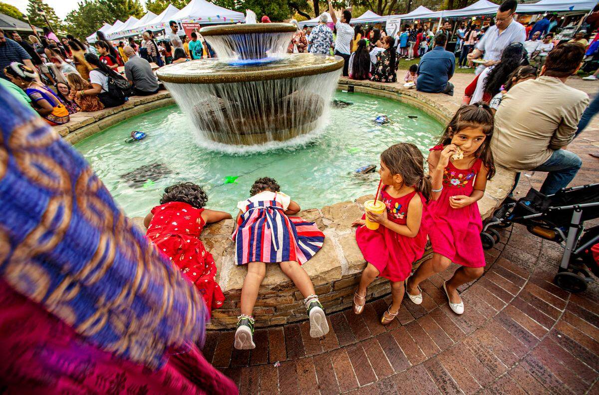 Thousands joined the celebration of Diwali at the Rustin Pavilion in the Southlake Town Square Saturday, Oct. 22, 2022. Nipa Guswarambi, 6, left, joins younger sister, Dhiti, 3, at the fountain, while Priya Abbott, 6 and older sister, Roma, enjoy sweet treats.