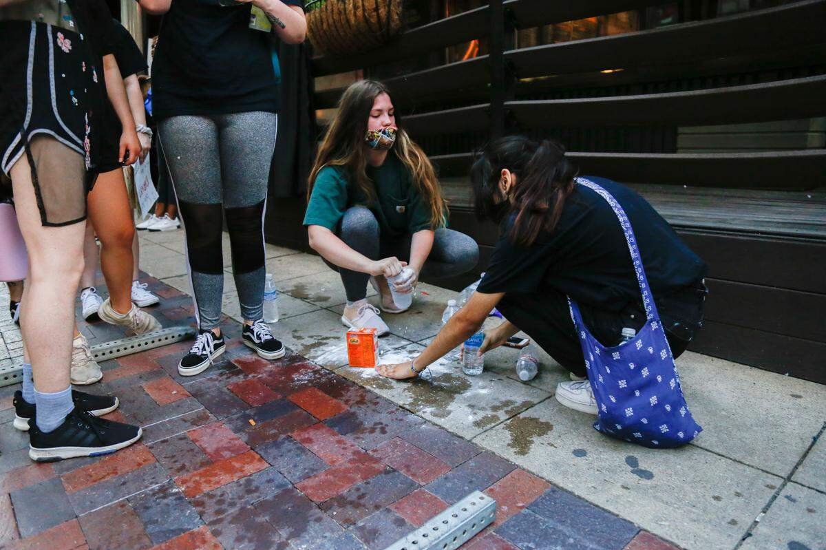 Elaine Sury, 23 of Denton, makes a baking soda and water solution to get tear gas out of the eyes of demonstrators during Dallas protests May 30. Demonstrators gathered to rebuke police for the treatment of George Floyd, a man who died in police custody in Minnesota.