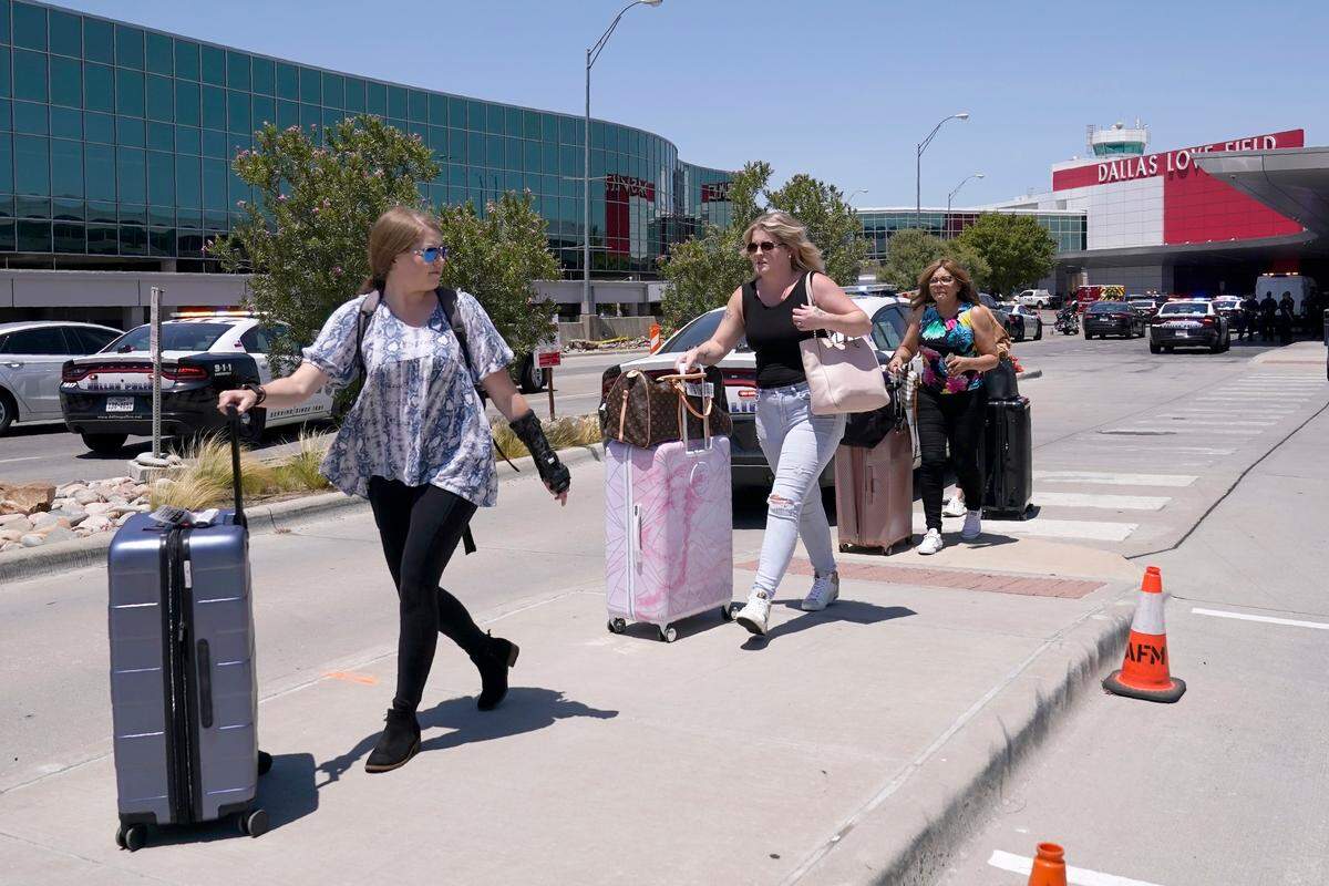 Travelers walk to a parking area outside of Dallas Love Field in Dallas, Monday, July 25, 2022. A 37-year-old woman fired several gunshots, apparently at the ceiling, inside of Dallas’ Love Field airport on Monday before an officer shot and wounded her, authorities said. (AP Photo/Tony Gutierrez)