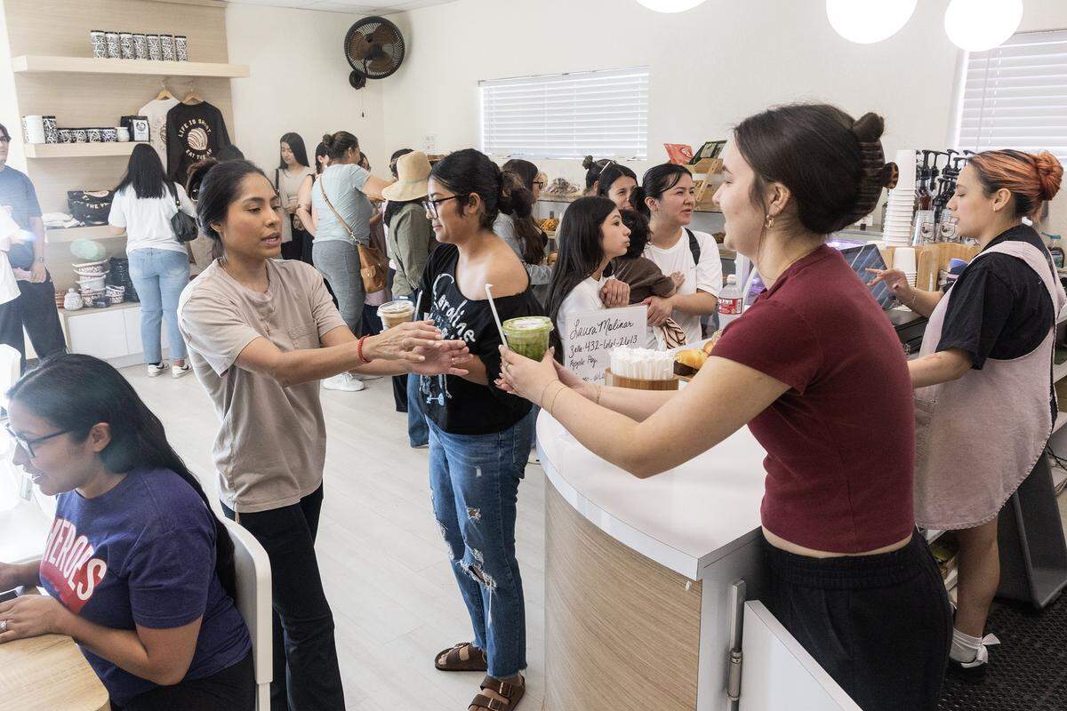 A barista serves customers their drinks during service.