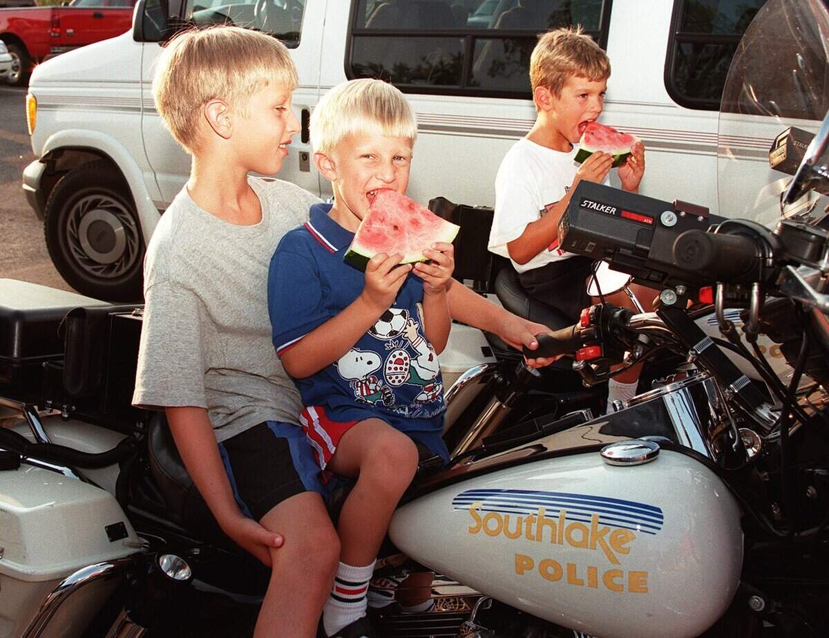 July 12, 1999: John Mercer, 8; Max Mercer, 4; and Clarke Overlander eat watermelon and sit on police bikes.