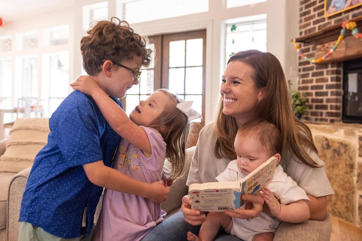 Siblings Wells, 7, Annie, 4, and Russ Morey, 6 months, read a book with their mother, Courtney, in the living room of their home on March 28. The family has been in a legal battle with Aledo ISD because they oppose an IQ test for Annie, who has Down syndrome, fearing it could limit her potential in special education.
