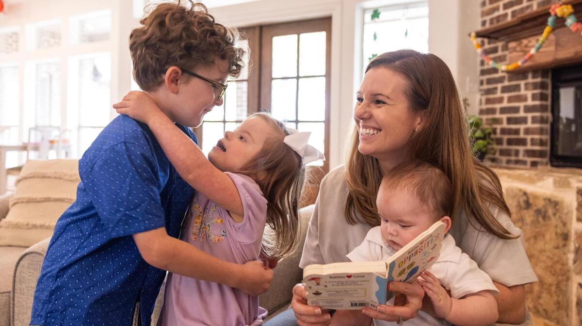 Siblings Wells, 7, Annie, 4, and Russ Morey, 6 months, read a book with their mother Courtney in the living room of their home on March 28. The Morey family has been in a legal battle with Aledo ISD because they oppose an IQ test for Annie, who has Down syndrome, fearing it could limit her potential in special education.