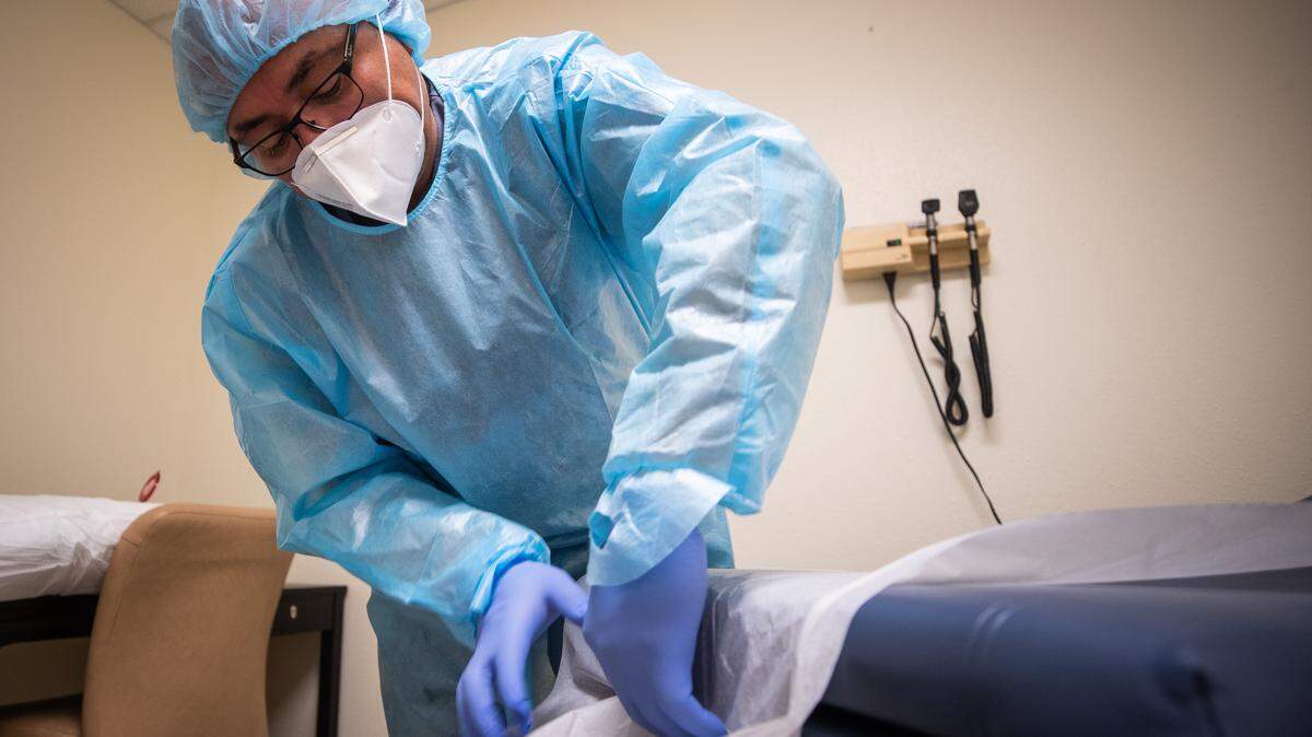 José Romeo Sosa, administrador de la Clínica Hispana Tu Salud en el Northside de Fort Worth, acomoda la cobertura protectora después de limpiar una cama con desinfectante.