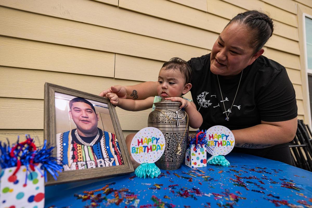 Erica Silva holds her grandson, Zechariah Emilio, next the urn and photo of her son, Zechariah Trevino, during the baby’s 1st birthday party in Newark, Texas, in September. Trevino was killed in a shooting outside of a Fort Worth Whataburger, stemming from a social media dispute, in January 2023.