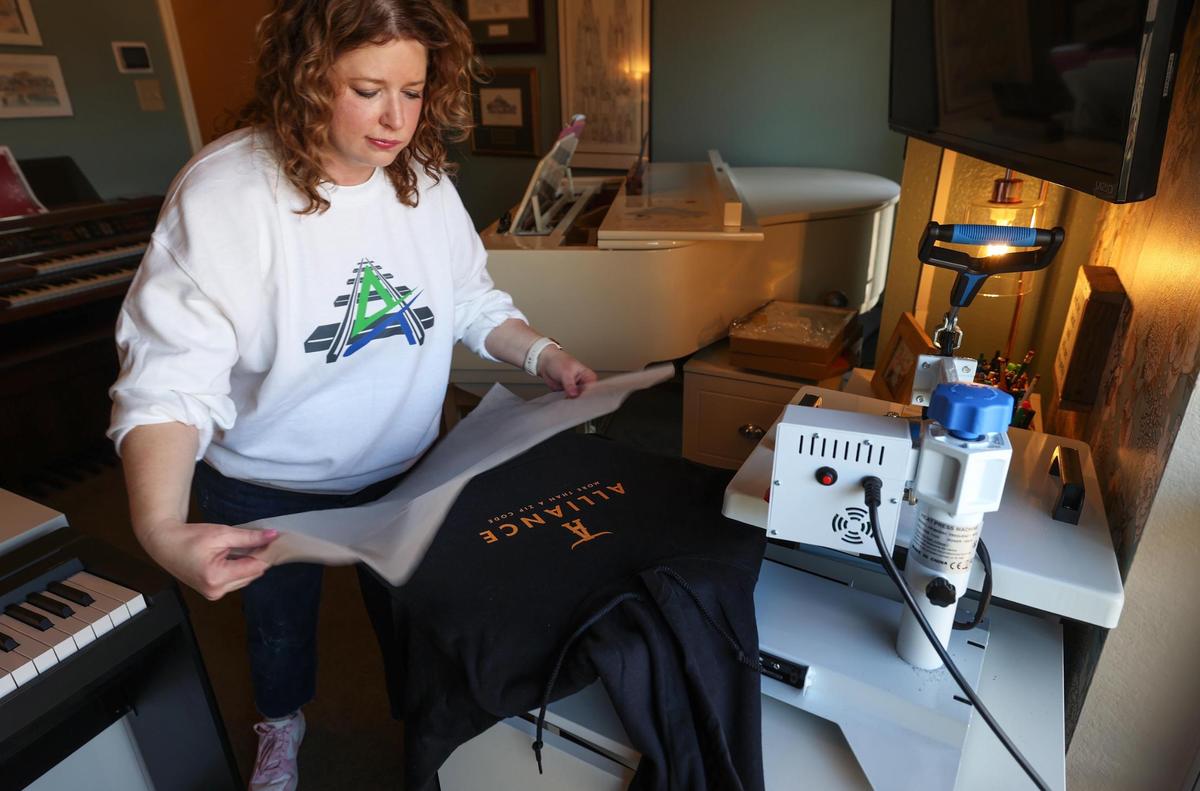 Michelle Gibson, a graphic designer, screen prints one of her Alliance-brand designs unto a hoodie at her home on Thursday, Jan. 16, 2025. Gibson created merchandise after hearing about the proposed plan to split the Keller school district. Gibson said she was inspired by the parody Alliance ISD Facebook page created in response to the plan.